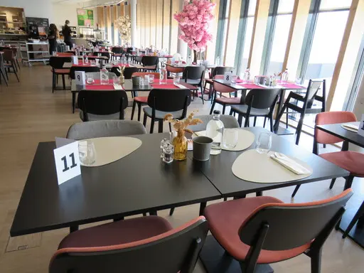 Tableau de brunch, assiettes, verres et couverts, vue sur la salle intérieure et coin buffet.